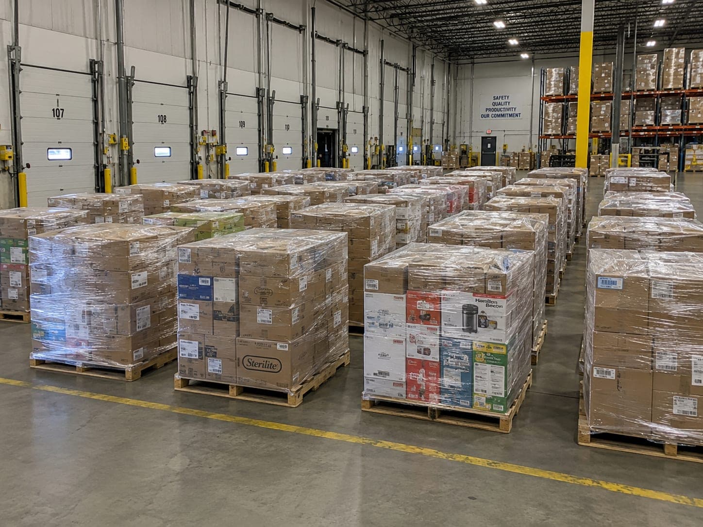 Long rows of shrink-wrapped pallets filling a warehouse for a full truckload order